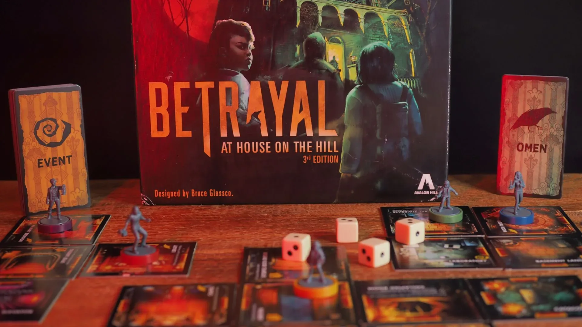 The Betrayal at House on the Hill box, dice, tokens, and board pieces on a wooden table