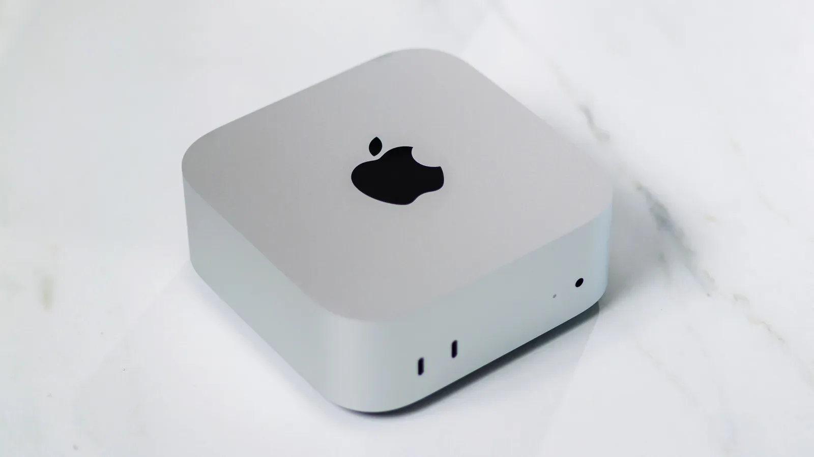 A compact Mac mini desktop connected to a monitor, keyboard and mouse on a desk