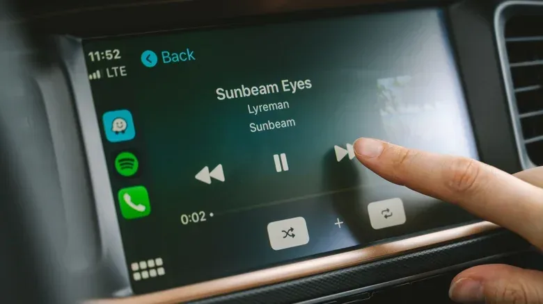 Spotify app on Apple CarPlay, with a finger touching the fast-forwarding button on a song.