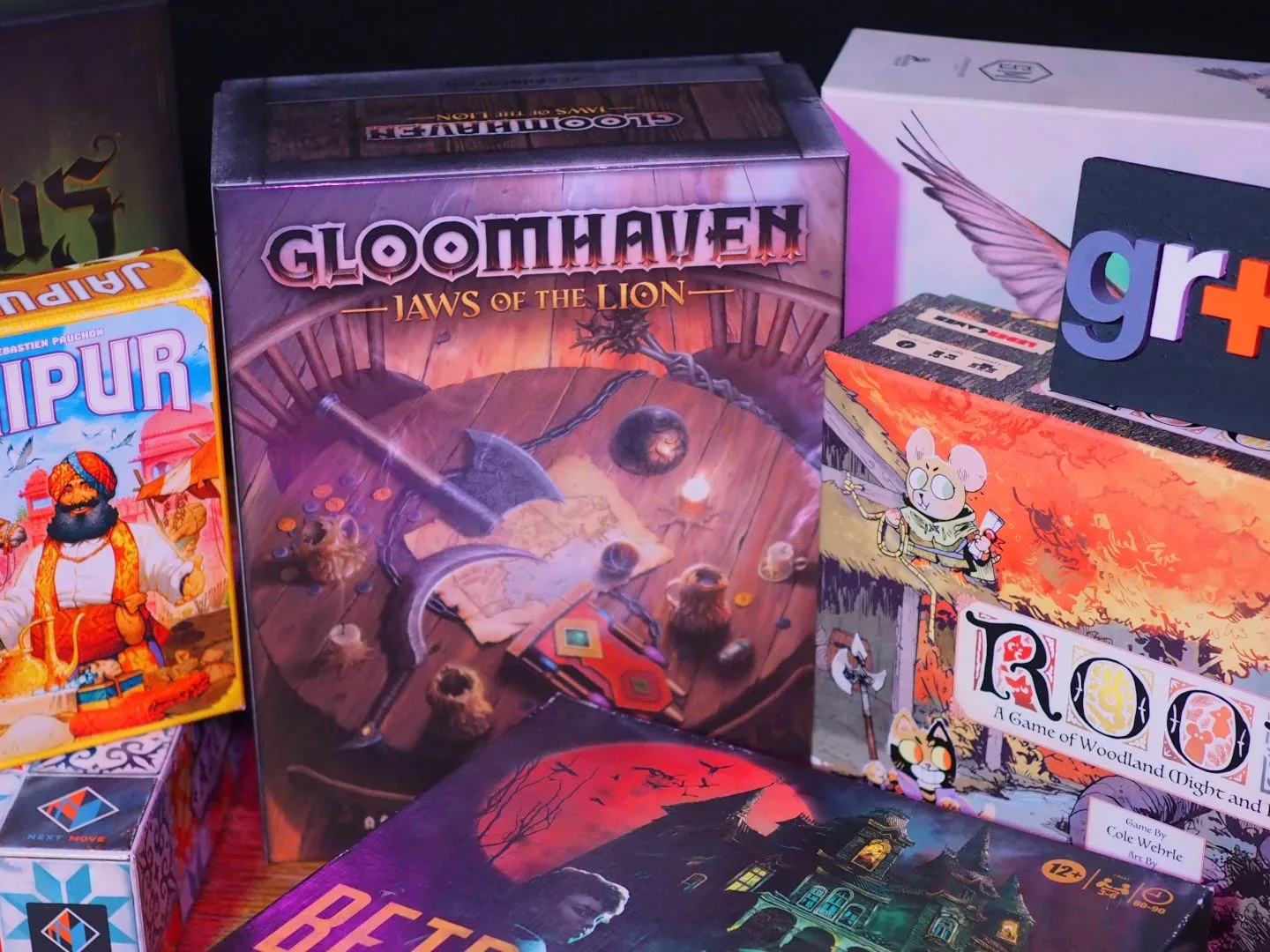 A collection of the best board games, standing in a row on a wooden table and against a dark background, with a GamesRadar+ logo visible