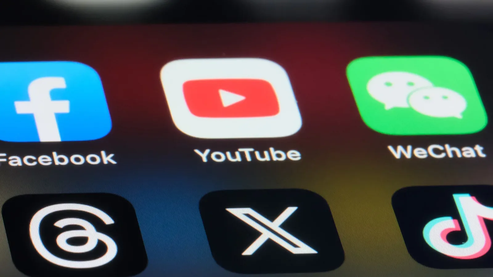A smartphone displaying social media apps beside an age-verification screen