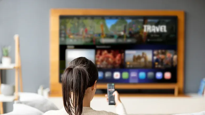 A console connected to a 4K TV beside window blinds arranged to reduce screen glare