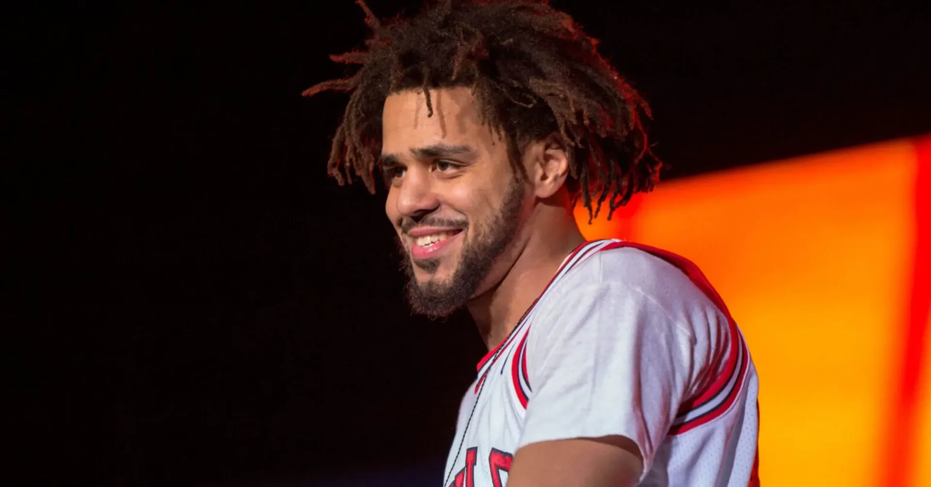 J. Cole performing on stage under concert lighting