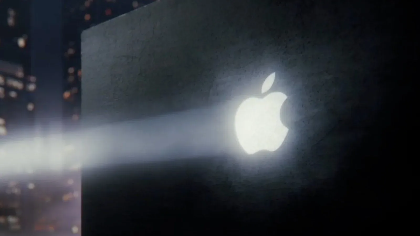Apple logo projected on a wall against a city skyline in a MacBook teaser