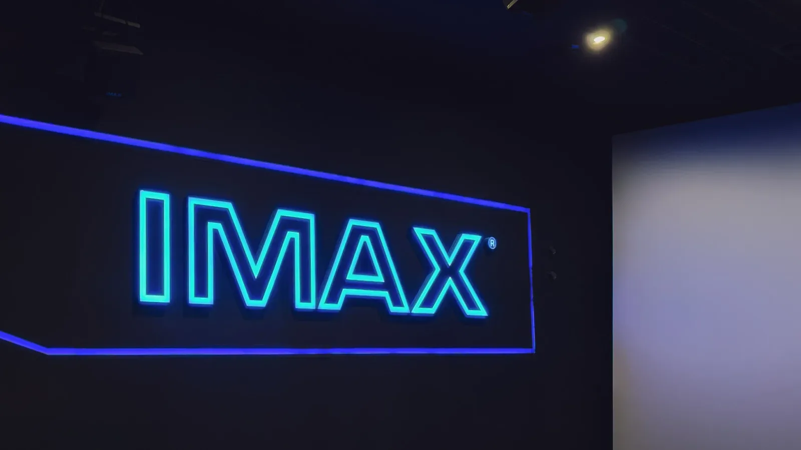A large-format cinema auditorium with a towering screen and rows of seats