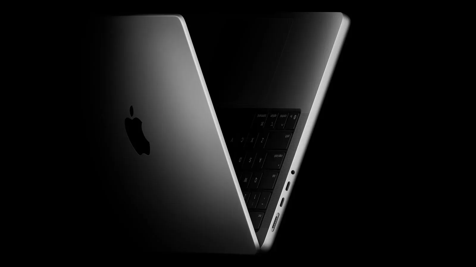 Closed MacBook Pro-style laptop on a desk, representing reports of a lighter OLED touchscreen model