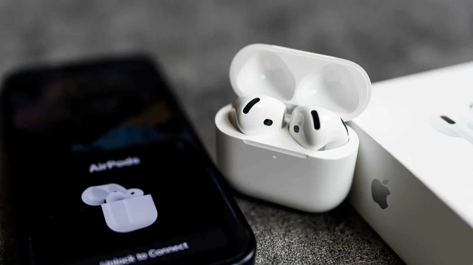 AirPods charging in their case beside an iPhone