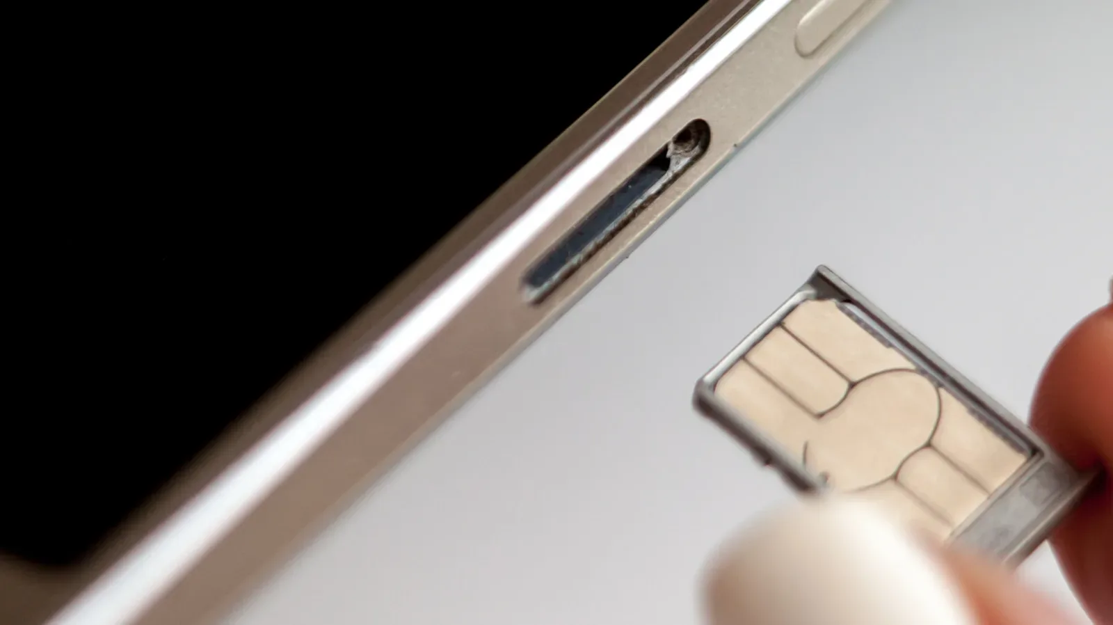 A smartphone SIM tray beside a SIM-eject tool and a physical SIM card