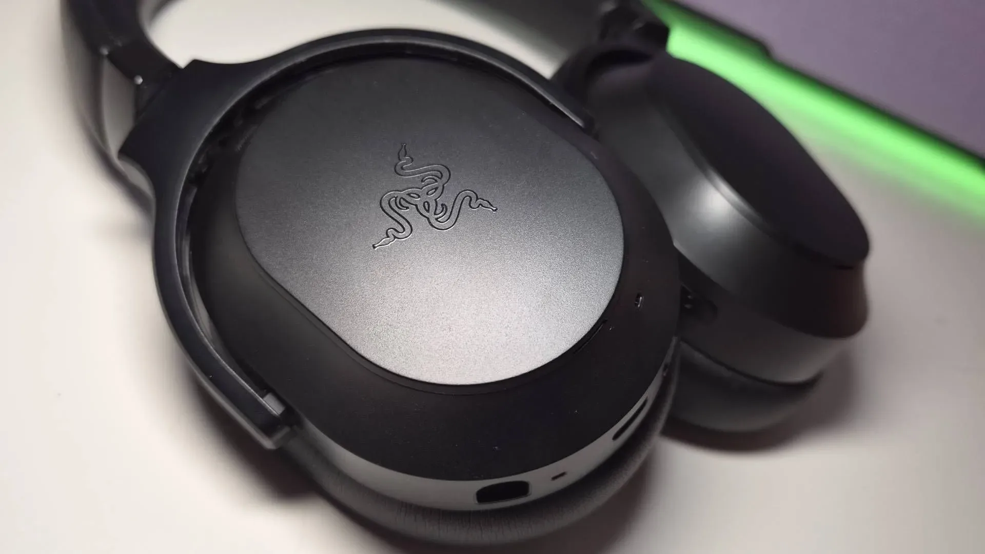 Razer Barracuda V2 Pro gaming headset with its left magnetic ear-cup cover removed to reveal dongle storage