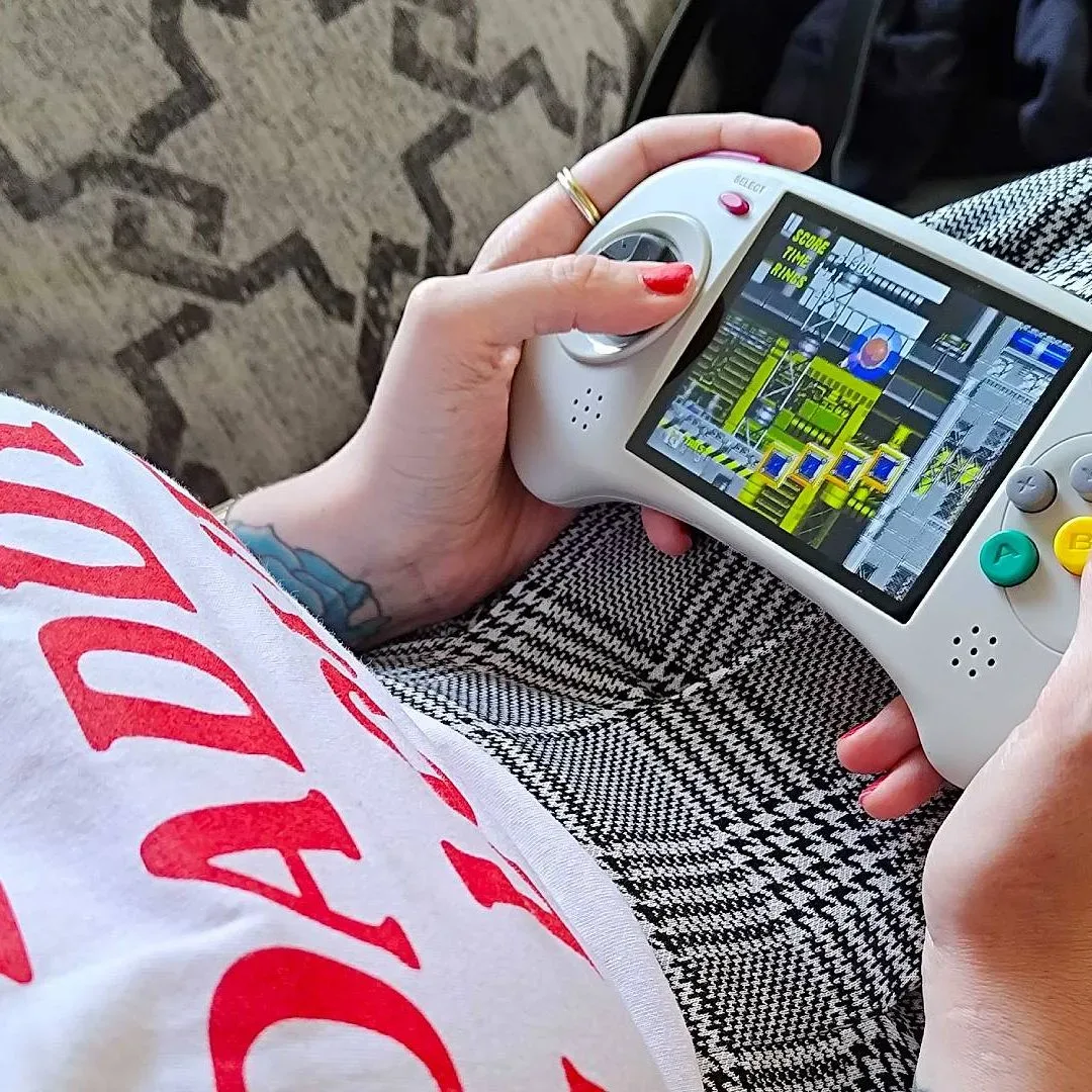 Hands holding Anbernic RG ARC-D with Sonic the Hedgehog 2 gameplay on screen.