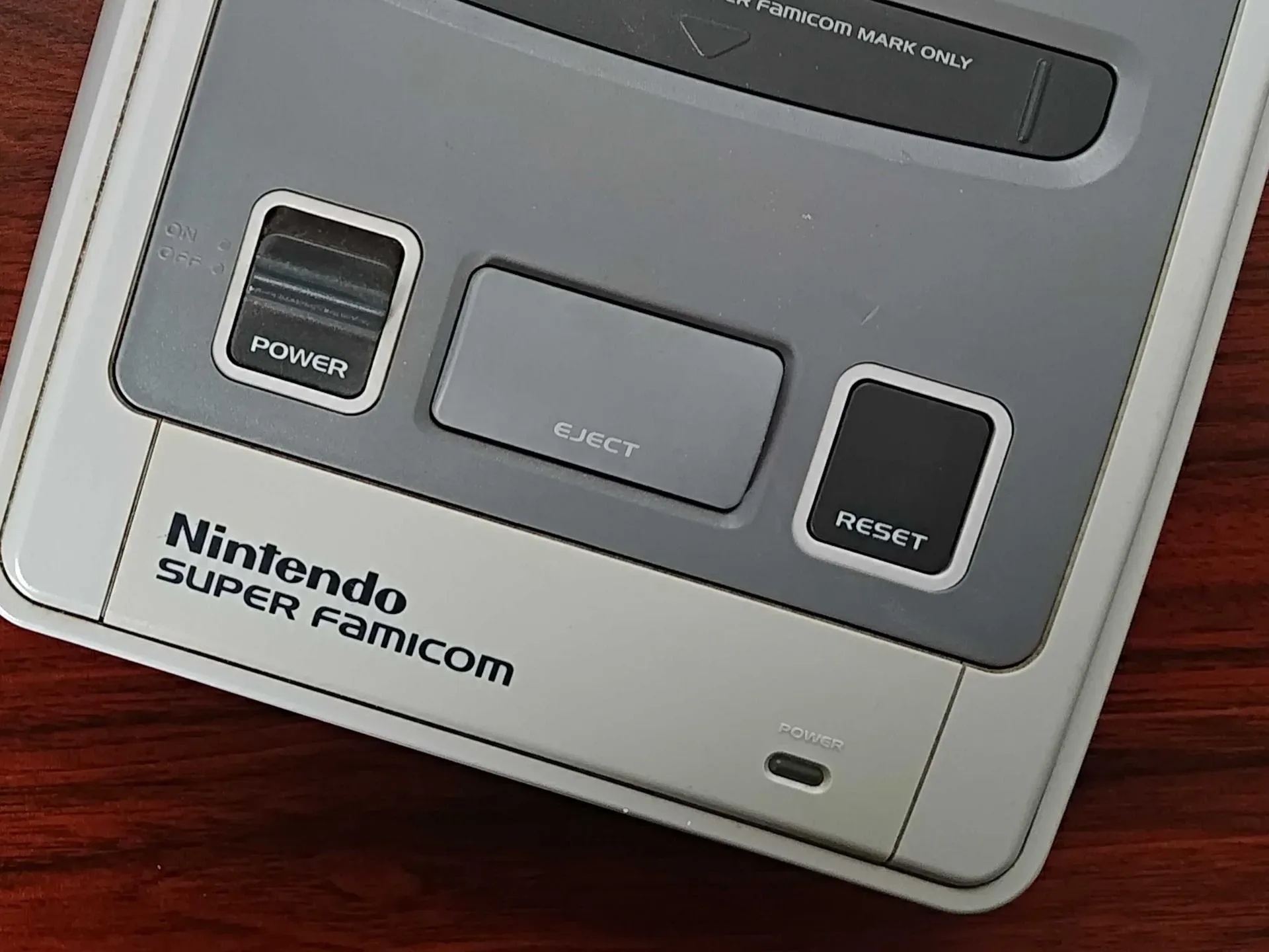 Close up of Super Famicom on woodgrain desk.