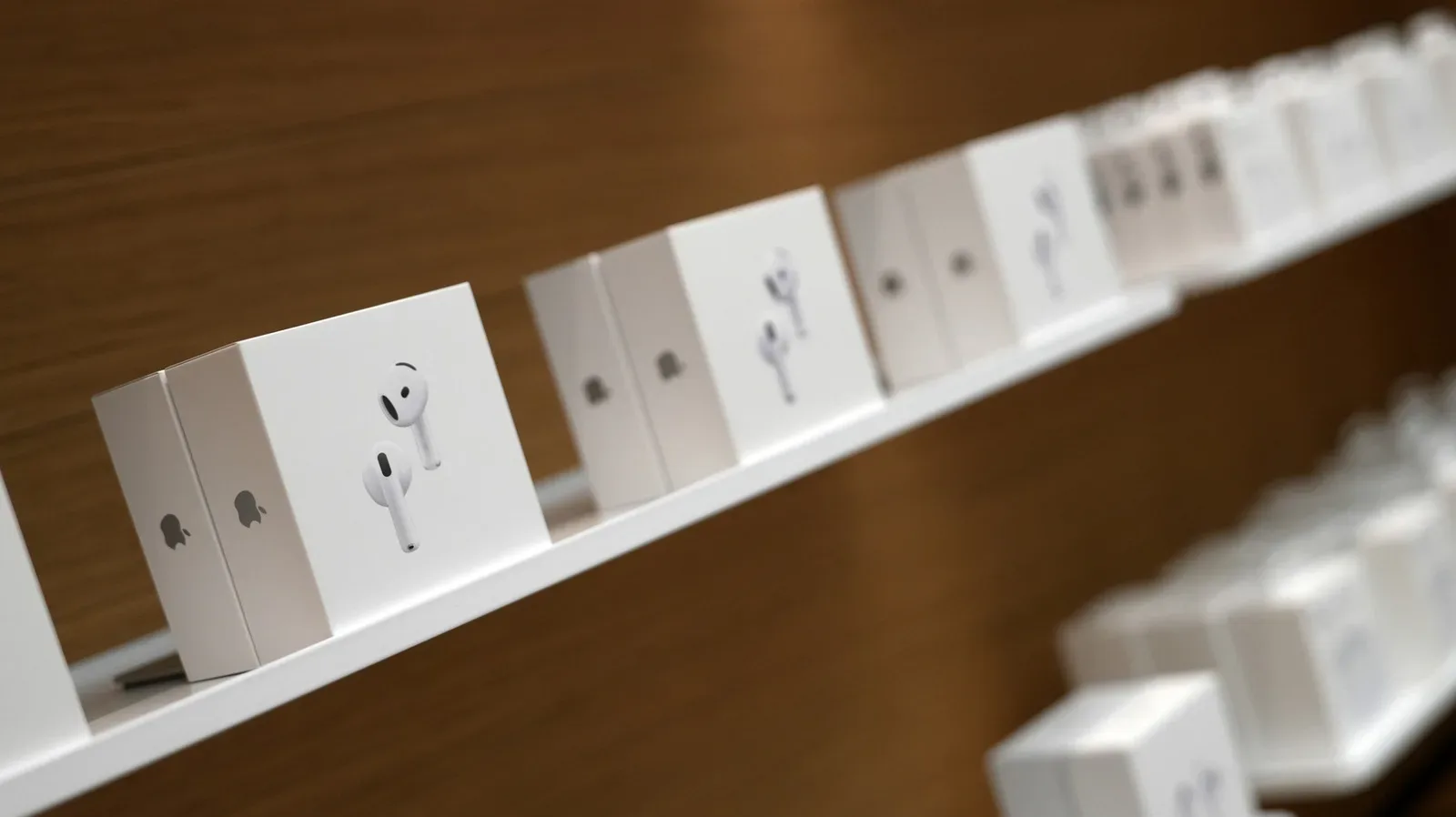 An AirPods charging case open beside an iPhone showing individual earbud battery levels