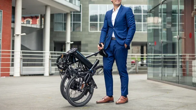 A man carrying a folded electric e-bike.