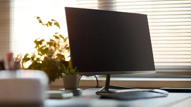 A laptop in a vertical stand connected to a monitor through a docking station