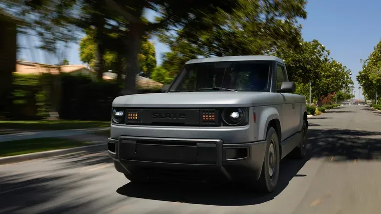 Electric pickup truck towing a small utility trailer on a paved road