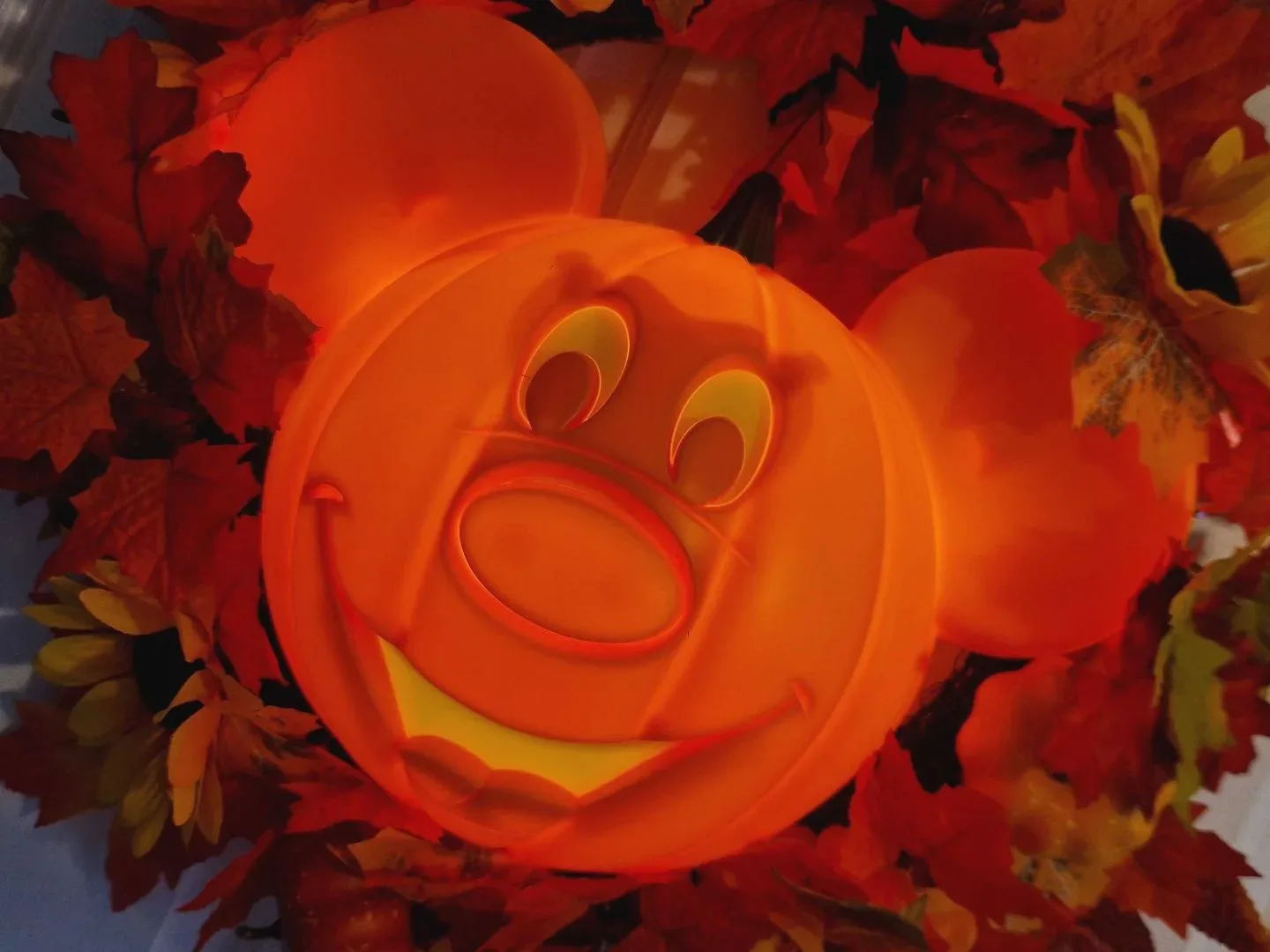Disney Mickey Mouse Halloween Wreath with a light-up pumpkin Mickey in the middle of autumnal leaves, hanging on a white door